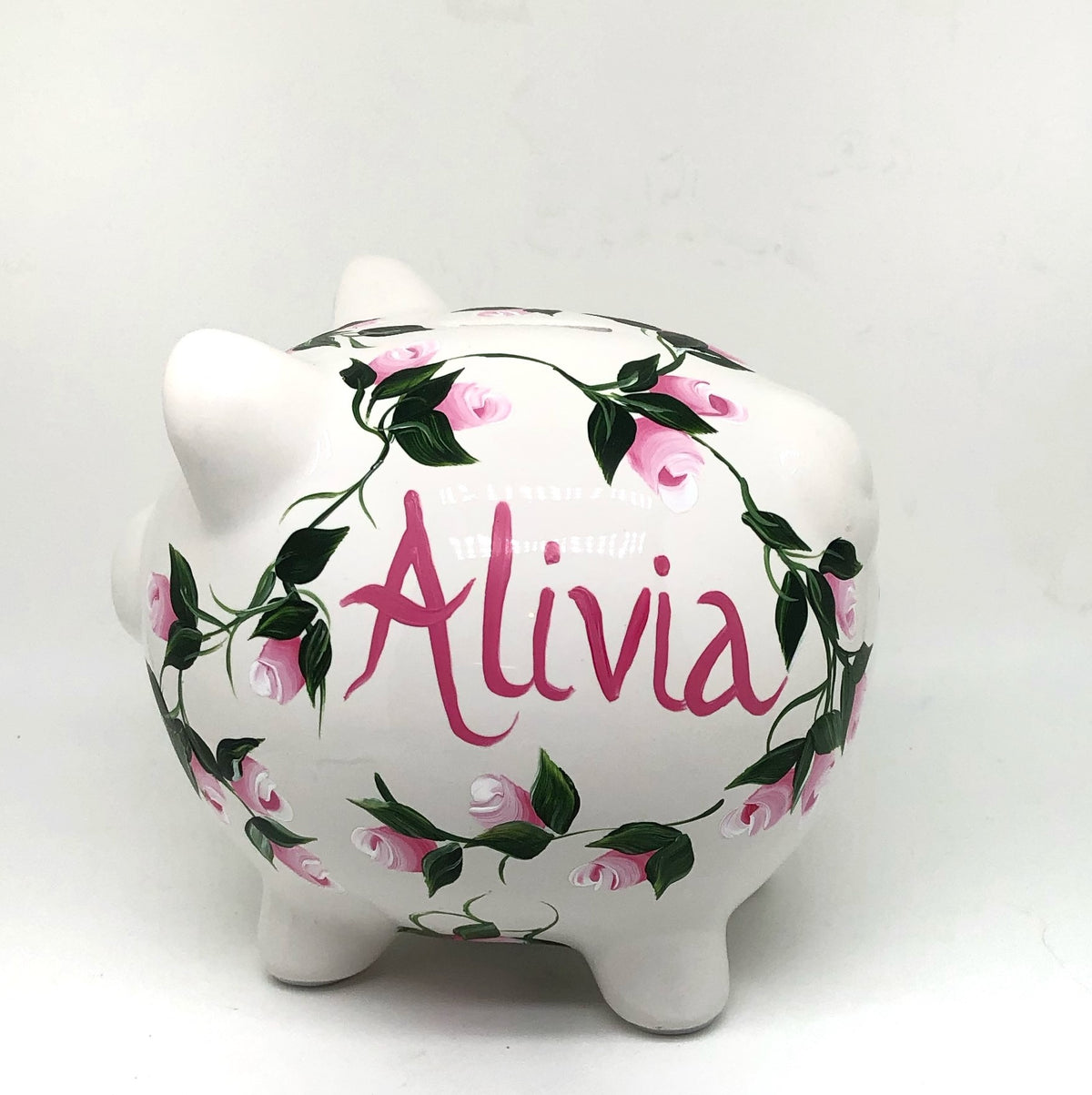 hand painted personalized piggy bank with pink rosebuds and green leaves and vines. A lovely new baby gift.