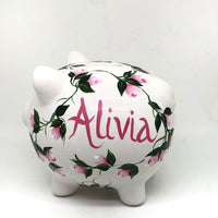 hand painted personalized piggy bank with pink rosebuds and green leaves and vines. A lovely new baby gift.