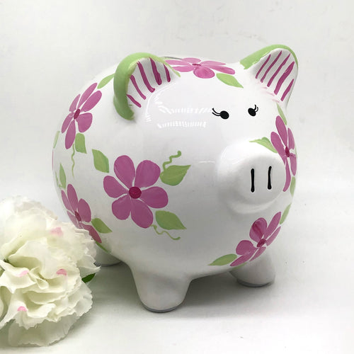hand painted personalized piggy bank with pink daisy flowers and sage green leaves and vines. A lovely new baby gift.