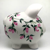 hand painted personalized piggy bank with pink rosebuds and green leaves and vines. A lovely new baby gift.
