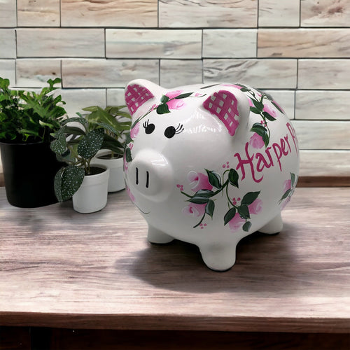hand painted personalized piggy bank with pink rosebuds and green leaves and vines. A lovely new baby gift.