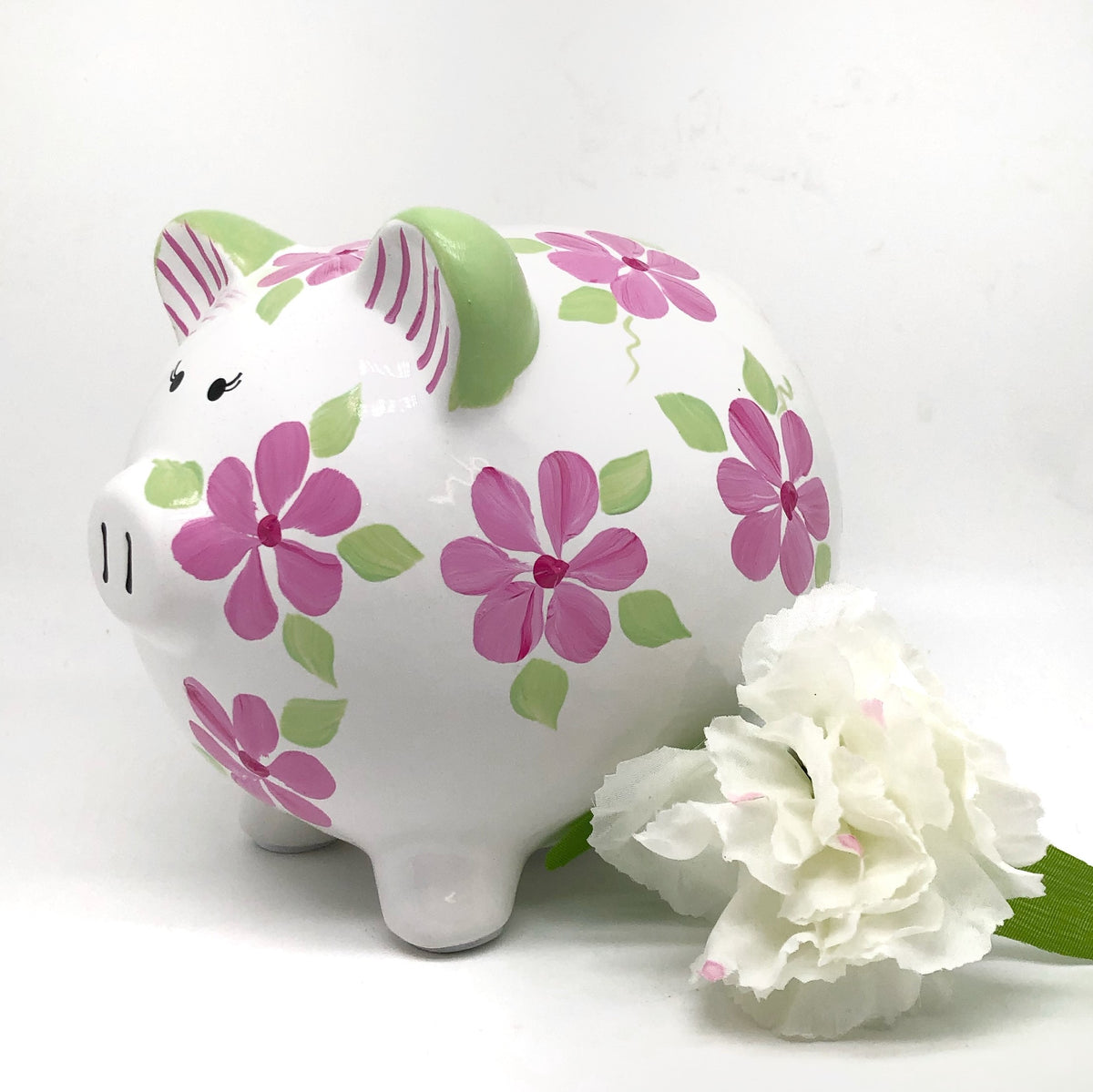 hand painted personalized piggy bank with pink daisy flowers and sage green leaves and vines. A lovely new baby gift.
