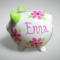 hand painted personalized piggy bank with pink daisy flowers and sage green leaves and vines. A lovely new baby gift.